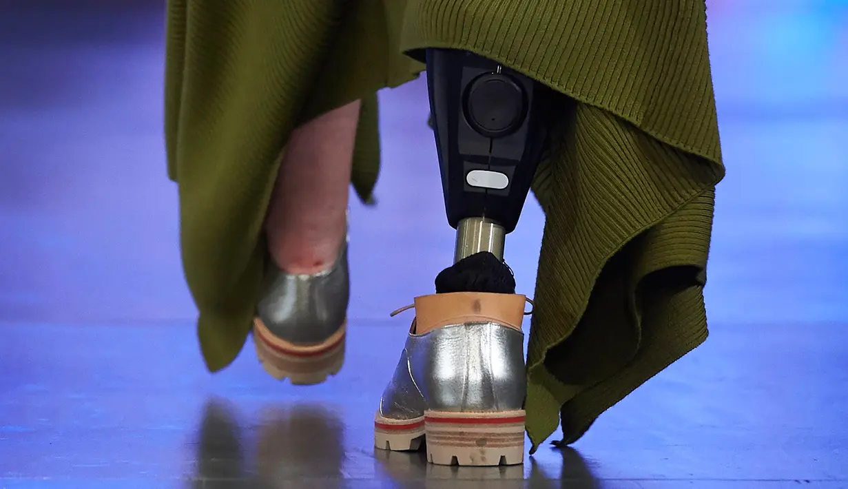 Sebuah kaki palsu yang dikenakan seorang model saat menampilkan koleksi Spring/Summer 2018 Teatum Jones pada hari pertama London Fashion Week, 15 September 2017. Model tersebut memakai gaun panjang warna hijau lumut dan kaki palsu. (NIKLAS HALLE'N/AFP)