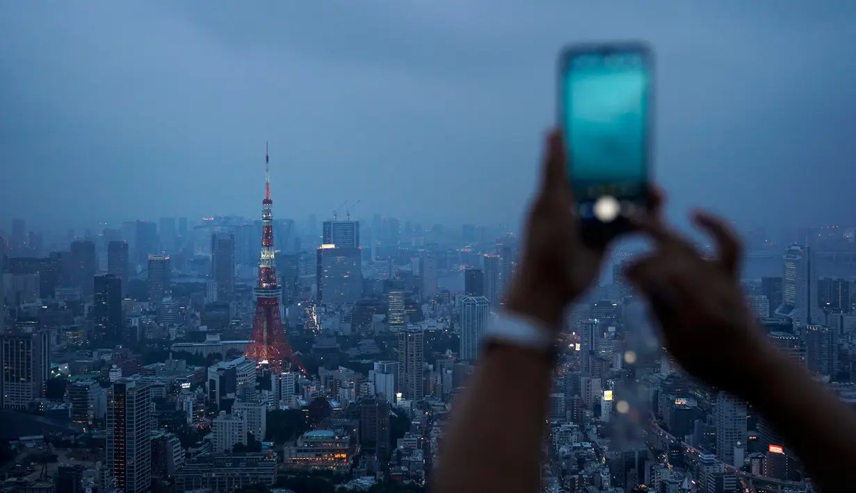 Gambar pada 19 Agustus 2019 memperlihatkan seorang turis mengambil gambar panorama skyline (kaki langit) kota Tokyo dari dek observasi Menara Roppongi Hills. Wisatawan dapat melihat berbagai gedung pencakar langit yang semua tertata rapi di kota terkenal sibuk ini. (AP Photo/Jae C. Hong)