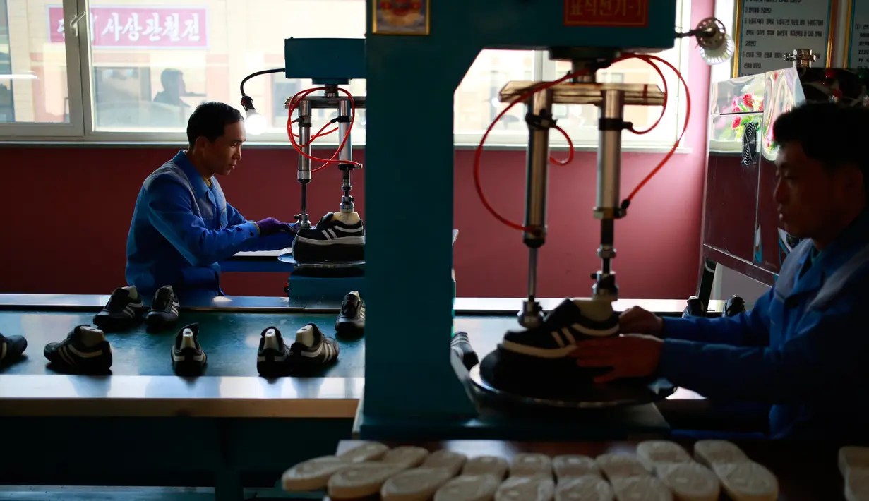 Dua pekerja mengoperasikan mesin menyelesaikan pembuatan sepatu di Pabrik Sepatu Ryuwon di Pyongyang, Korea Utara (1/2). Pabrik Sepatu Ryuwon merupakan spesialisasi dalam sepatu olahraga. (AP Photo/Dita Alangkara)