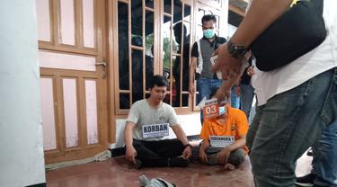 Dua pelaku pembunuhan terhadap pria yang jasadnya ditemukan di dalam karung mengambang di Danau Gawir, Kabupaten Tangerang menjalani reka adegan, Kamis (2/6/2022). (Liputan6.com/Pramita Tristiawati)