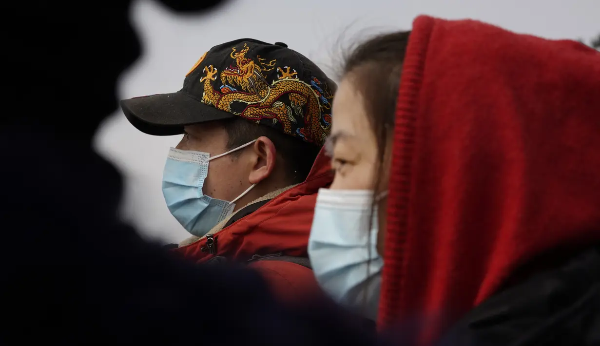 Pengunjung mengenakan masker saat mereka menikmati pemandangan dari taman Jingshan pada hari bersalju di Beijing, China, Selasa (19/1/2021). China sekarang berurusan dengan pandemi virus corona di timur lautnya yang dingin, mendorong penguncian ketat dan pembatasan perjalanan. (AP Photo/Ng Han Guan)