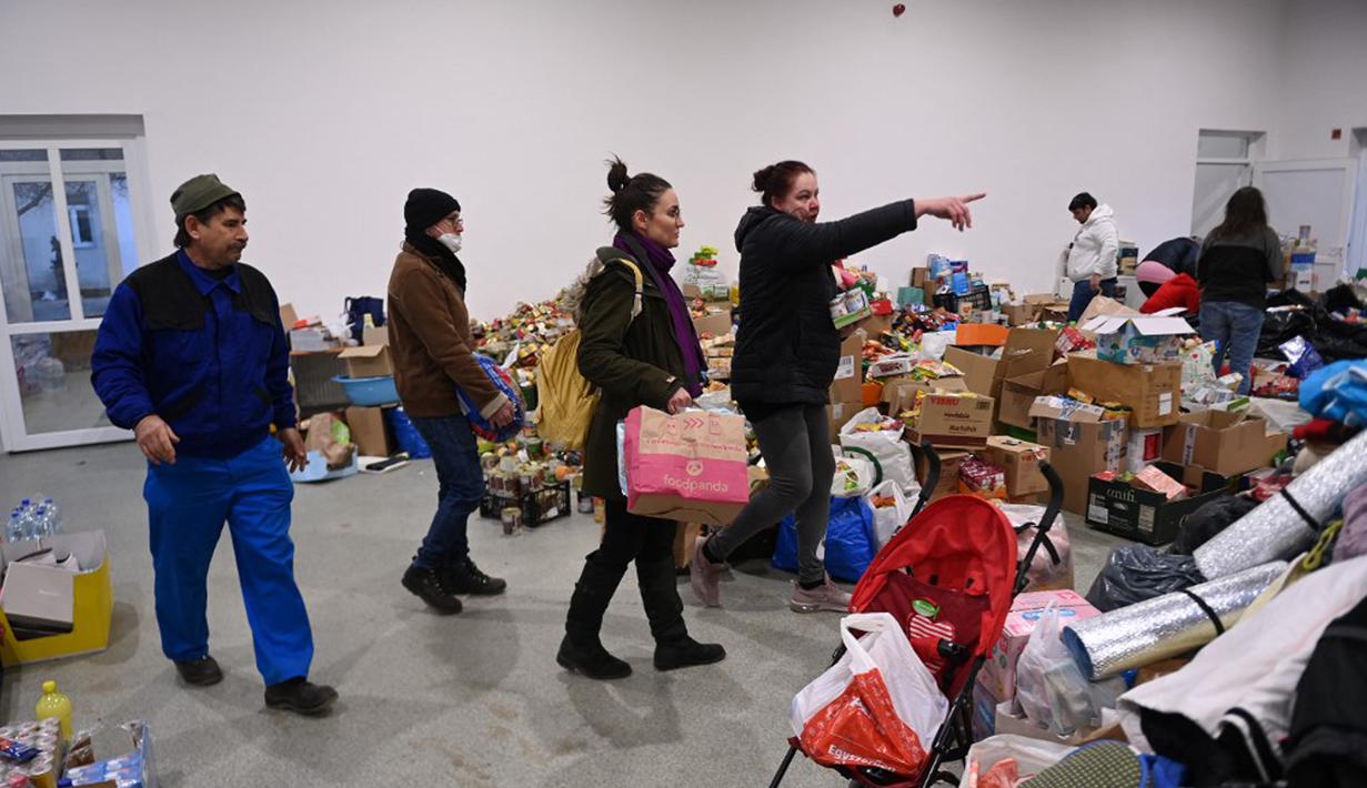 Orang-orang membawa sumbangan ke pusat pengungsian sementara di sekolah dasar setempat di Tiszabecs, Hongaria timur, 28 Februari 2022. Warga Hungaria bergegas ke perbatasan Ukraina untuk membantu pengungsi yang melarikan diri dari invasi Rusia. (Attila KISBENEDEK/AFP)