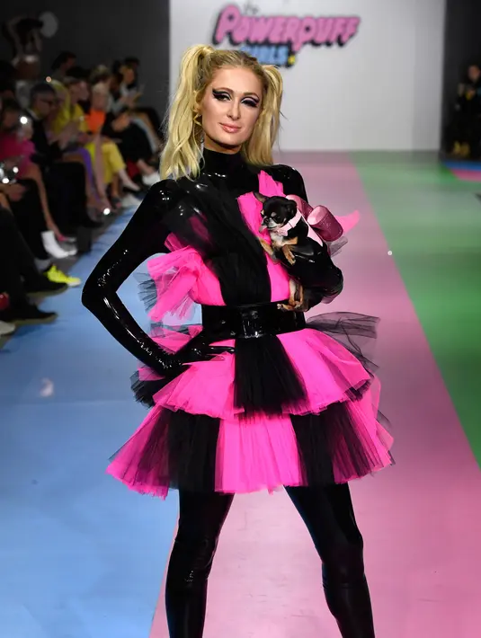 Paris Hilton membawa anjing saat tampil dalam Christian Cowan x The Powerpuff Girls Fashion Show, Los Angeles, AS, Jumat (8/3). Anjing tersebut terlihat seperti putri raja dengan simpul besar di tubuhnya. (Frazer Harrison/Getty Images North America/AFP)