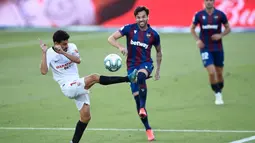 Pemain Sevilla, Jesus Navas, berusaha menghadang tendangan bek Levante, Tono, pada laga La Liga di Estadio Camilo Cano, Selasa (16/6/2020). Kedua tim bermain imbang 1-1. (AFP/Jose Jordan)