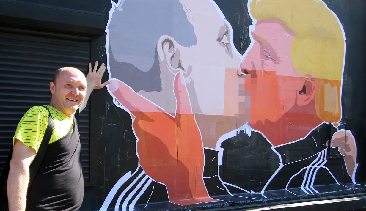 Warga berpose disamping mural calon Presiden AS, Donald Trump dan Presiden Rusia, Vladimir Putin sedang berciuman di Vilnius , Lithuania, (13/5). Hal ini diperkuat dengan pernyataan Trump bahwa Putin adalah pemimpin yang kuat. (AFP PHOTO/Petras Malukas)
