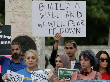 Pengunjuk rasa berdemontrasi di pusat kota Miami, AS, Kamis (26/1). Pengunjuk rasa menolak kebijakan Presiden AS, Donald Trump yang membatasi warga Muslim masuk ke AS. (AP Photo / Alan Diaz)