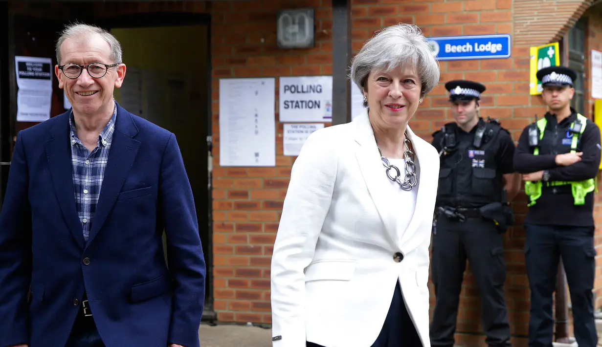 Perdana Menteri (PM) Inggris Theresa May bersama suaminya, Phillip, meninggalkan TPS Kota Maidenhead, Kamis (8/6). Sebanyak 650 anggota parlemen Westminster akan dipilih, dengan sekitar 46,9 juta orang terdaftar untuk memilih. (AP Photo/Alastair Grant)