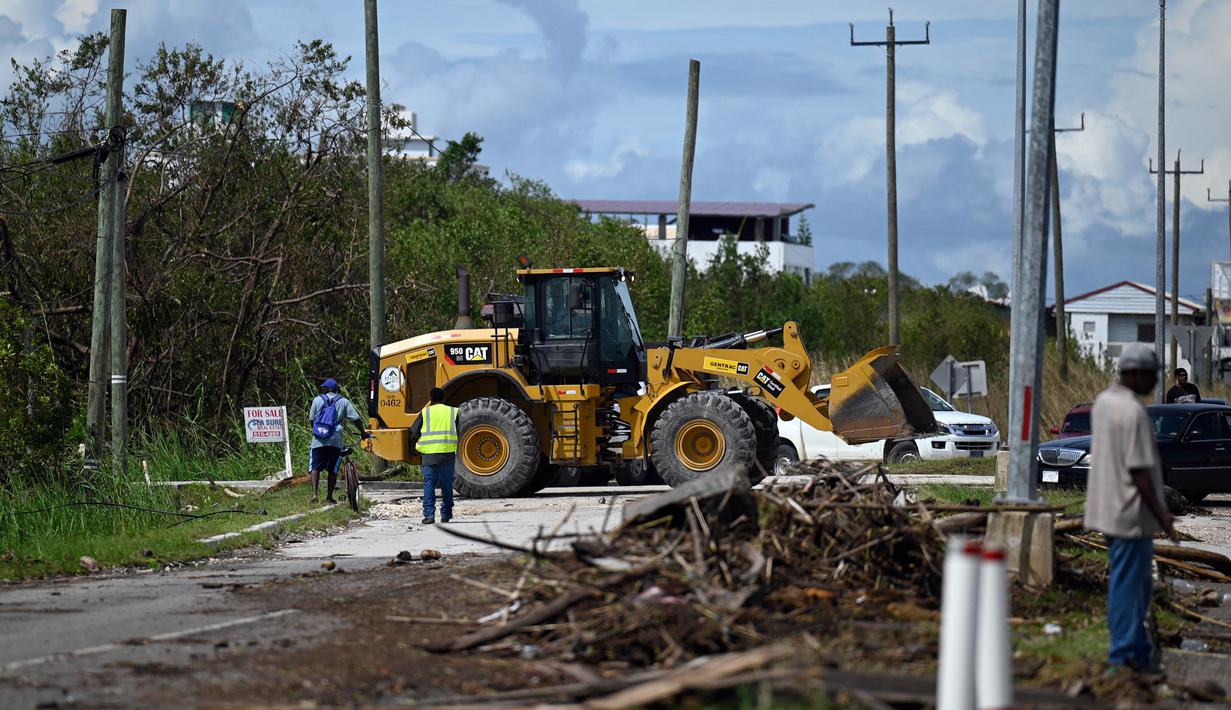 Pekerja memindahkan pohon dan cabang yang tumbang dari jalan raya setelah Badai Lisa di Belize City, Belize, 3 November 2022. Badai Tropis Lisa menyebabkan banjir dan membuat sebagian negara itu menjadi gelap gulita. (Johan ORDONEZ/AFP)