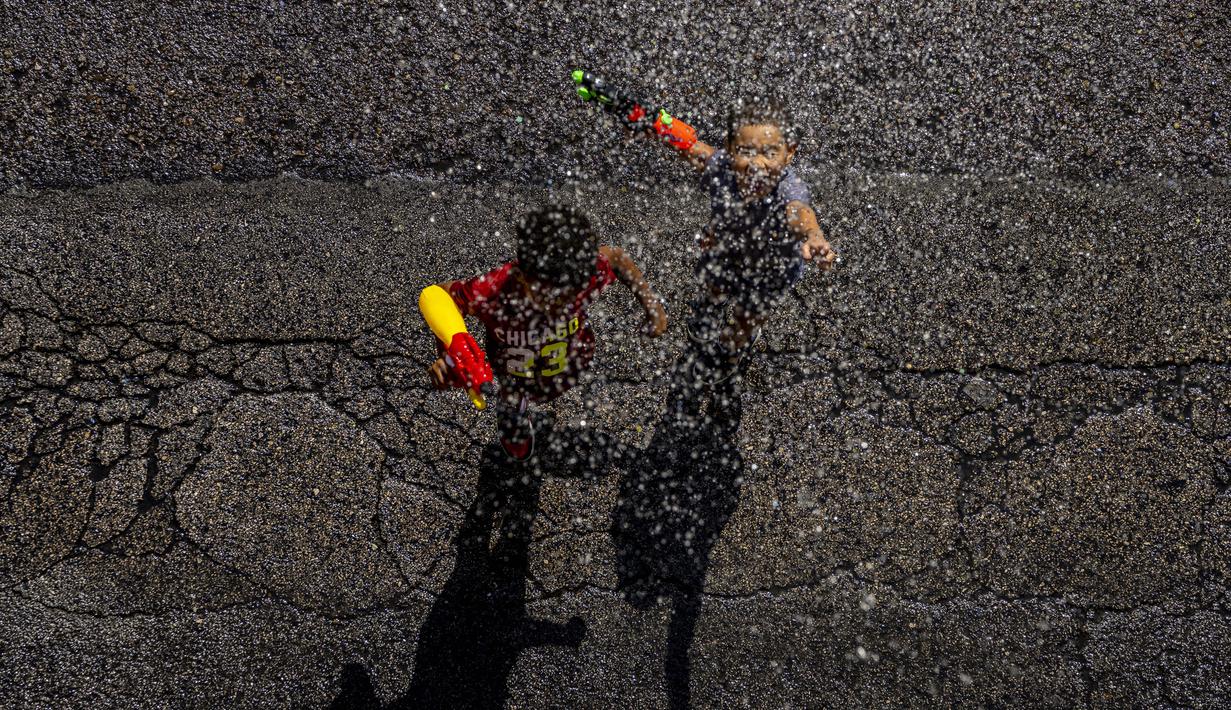 Anak-anak saling menyemprotkan air saat perang air tahunan di jalan-jalan lingkungan Vallecas, Madrid, Spanyol, 17 Juli 2022. Acara ini dimeriahkan dengan suara drum, peluit, teriakan, dan lagu. (AP Photo/Manu Fernandez)