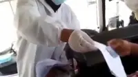 Seorang wanita membagikan hasil rapid antigen di bus. (Liputan6.com/ #sumsel_aktif)