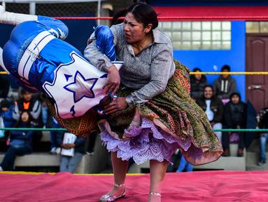 Pegulat Bolivia, Ana Luisa Yujra (kanan) membanting lawannya pegulat pria di atas ring gulat di El Alto, pada 24 November 2019. Di Bolivia ada sebuah atraksi gulat yang diperankan perempuan dengan menggunakan busana khas warga Bolivia. (Ronaldo SCHEMIDT / AFP)