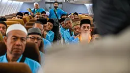 Para calon jemaah haji Indonesia memperhatikan cara menggunakan jaket penyelamat dari awak kabin di dalam pesawat Boeing 717 yang sudah tidak digunakan lagi selama sesi pelatihan keselamatan pra-keberangkatan di pusat embarkasi haji Banda Aceh pada Kamis 14 Mei 2026. (CHAIDEER MAHYUDDIN/AFP)