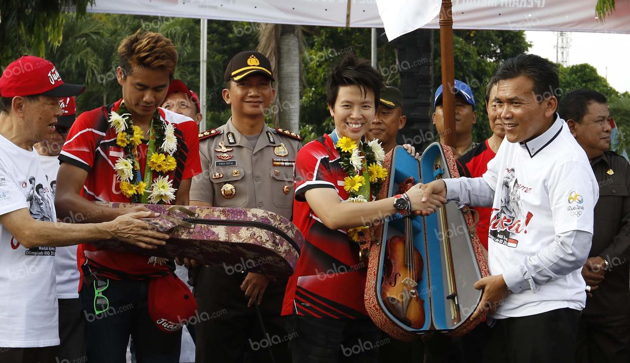 Peraih emas bulutangkis Olimpiade Rio 2016, Tontowi Ahmad dan Liliyana Natsir, mendapat souvenir khas Kudus yang diserahkan Bupati Kudus, Musthofa di alun-alun kota Kudus, Kamis (1/9/2016). (Bola.com/Arief Bagus)