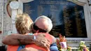 Dua warga asing berpelukan saat memperingati Tragedi Bom Bali I yang ke 14 di Monumen Ground Zero di Kuta, Bali, (12/10). Peristiwa ledakan bom di Jalan Legian ini merenggut 202 korban jiwa. (AFP Photo/ Sonny Tumbelaka)