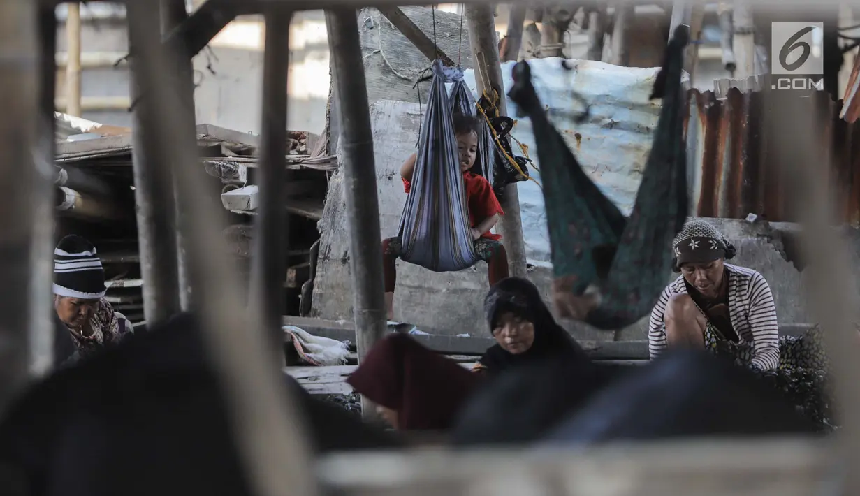 Seorang anak ikut menemani ibunya mengupas kerang hijau di Kampung Nelayan Muara Angke, Jakarta, Rabu (3/7/2019). Dengan penghasilan rata-rata Rp 30 ribu/hari, para buruh pengupas kerang hijau tersebut harus cukup memenuhi kebutuhan hidup keluarganya. (Liputan6.com/Faizal Fanani)