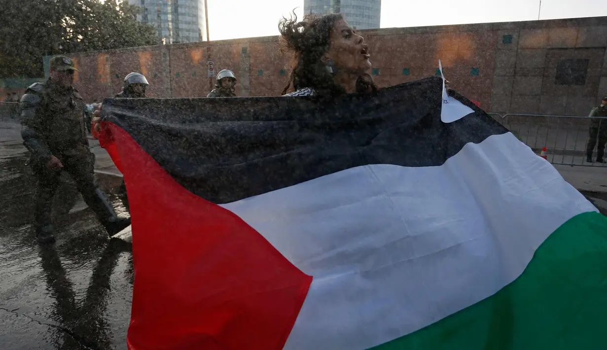 Seorang wanita membentangkan bendera Palestina saat unjuk rasa memprotes kebijakan Presiden AS, Donald Trump soal Yerusalem sebagai ibu kota Israel di luar Kedubes AS di Santiago, Chile, (11/12). (AP Photo / Luis Hidalgo)