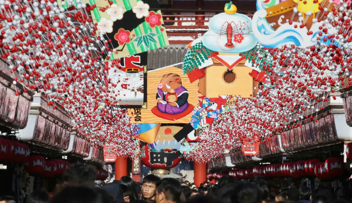 Pejalan kaki melintas di bawah dekorasi shio babi tanah yang mengarah ke kuil Buddha Asakusa Sensoji di Tokyo, Jepang, Kamis (27/12). Tahun 2019 masuk ke dalam shio babi tanah. (AP Photo/Koji Sasahara)