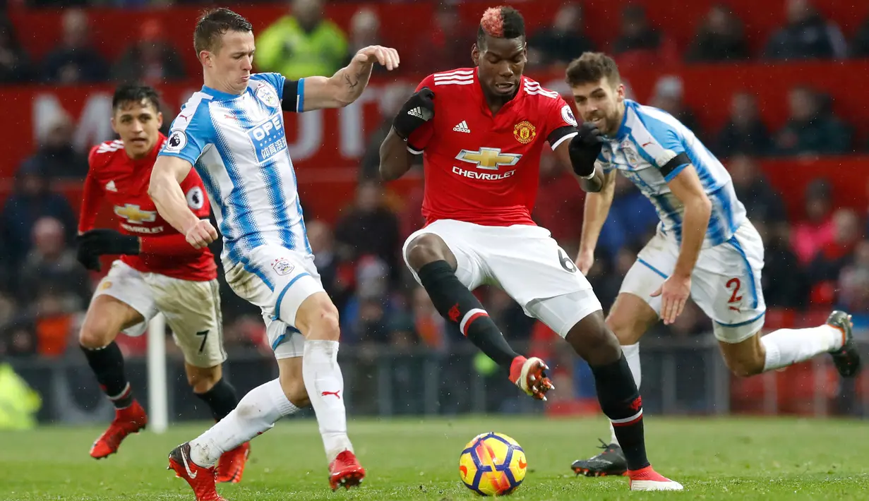 Pemain Manchester United Paul Pogba berusaha melawati dua pemain Huddersfield Town saat pertandingan Liga Inggris di Old Trafford di Manchester (3/2). Tiga poin dari Huddersfield membuat Manchester United mengoleksi 56 poin. (Martin Rickett / PA via AP)