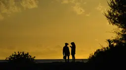 Pasangan menikmati matahari terbenam di pantai Lhoknga di provinsi Aceh (3/5/2019). Pantai Lhoknga memiliki ombak yang besar dan garang sehingga membuatnya jadi sangat terkenal di kalangan komunitas selancar internasional. (AFP Photo/ Chaideer Mahyuddin)