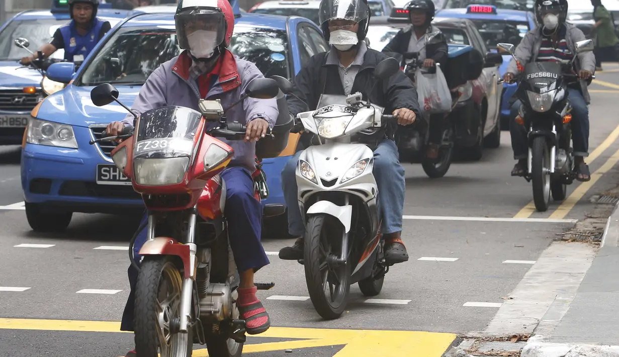Warga Singapura menggunakan masker saat menjalankan aktivitas Singapura, Selasa (29/9/2015). Badan Lingkungan Hidup Nasional Singapura meningkatkan level kabut asap menjadi sangat tidak sehat (REUTERS/Edgar Su)