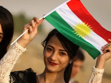 Seorang gadis Kurdi Iran memegang bendera Kurdi saat mengampanyekan referendum untuk kemerdekaan di kota Bahirka, Irak Utara (21/9). Mereka meminta referendum untuk menentukan kemerdekaan etnis Kurdi di Irak. (AFP Photo/Safin Hamed)