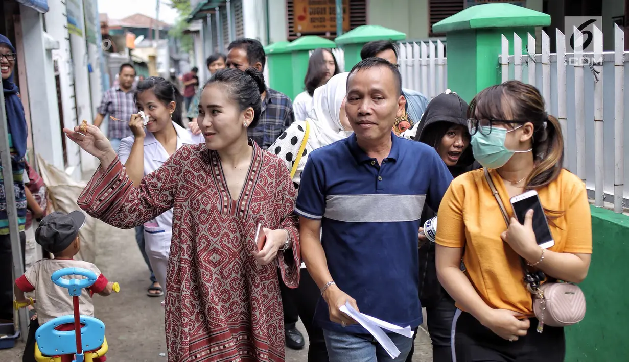 Penyanyi dangdut Ayu Ting Ting bersama sang ayah, Abdul Rozak dan adiknya, Assyifa Nuraini berjalan menuju TPS 5 untuk menggunakan hak pilih mereka pada pelaksanaan Pilkada Serentak 2018 Sukma Jaya, Depok, Rabu (27/6). (Liputan6.com/Faizal Fanani)