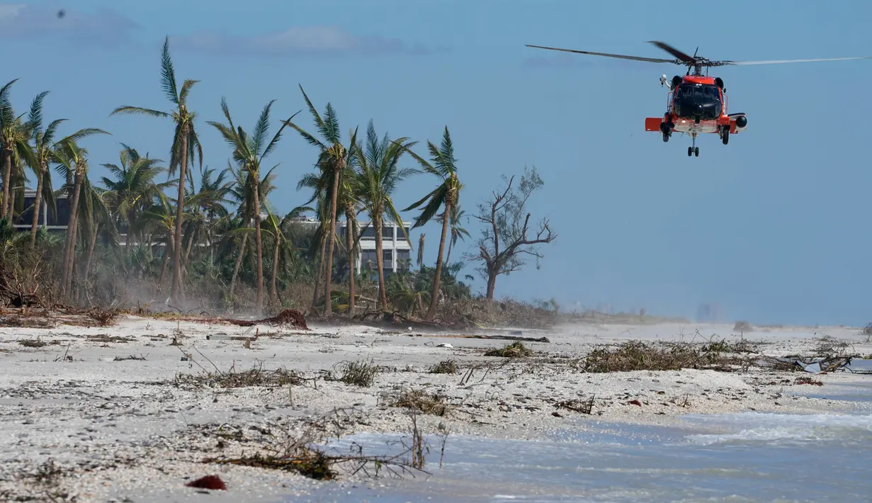 Helikopter Penjaga Pantai AS bersiap untuk mendarat di pantai untuk mengangkut orang-orang dari pulau itu setelah Badai Ian di Pulau Sanibel, Florida, Amerika Serikat, 30 September 2022. Kehancuran yang menimpa Florida menjadi fokus utama sehari setelah badai ini menghantam dengan kategori 4 yang dahsyat, salah satu badai terkuat yang pernah melanda AS. (AP Photo/Steve Helber)