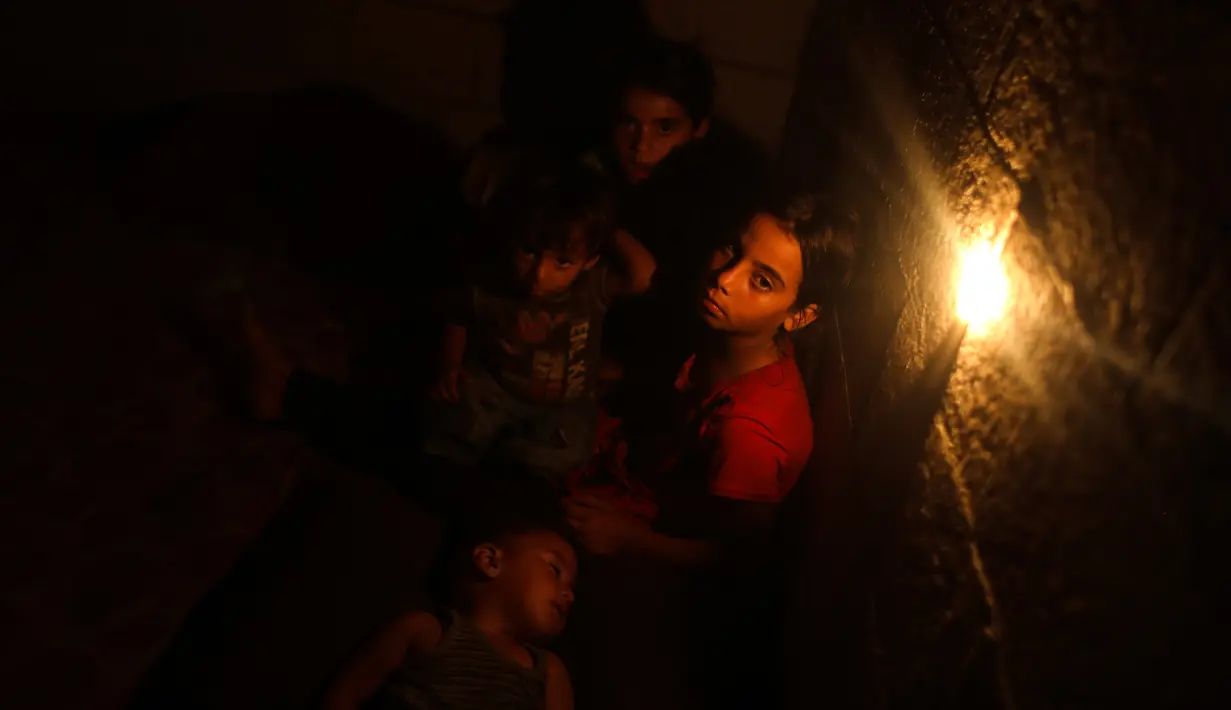 Anak-anak Palestina terlihat di dalam rumah mereka saat pemadaman listrik terjadi di Kota Khan Younis, Jalur Gaza selatan, pada 18 Agustus 2020. Satu-satunya pembangkit listrik di Jalur Gaza telah sepenuhnya berhenti beroperasi akibat kehabisan bahan bakar. (Xinhua/Yasser Qudih)