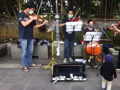 Musisi lokal Bogor memainkan musik klasik di pedestrian Kebun Raya, Jalan Pajajaran, Bogor, Jawa Barat, Minggu (14/6/2020). Untuk memenuhi kebutuhan hidup akibat sepinya job pertunjukan selama pandemi COVID-19, mereka memilih mengamen saat warga berolahraga. (merdeka.com/Arie Basuki)