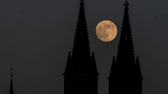 Bulan purnama terbit di belakang Basilika Santo Petrus dan Santo Paulus, bagian dari Kastil Vysehrad, di Praha, Republik Ceko, pada hari Selasa 25 Mei 2021 (Michal Cizek / AFP / Getty)