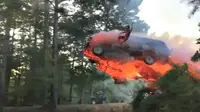 Sebuah video menayangkan gerakan lambat ketika sebuah SUV melesat ke udara sambil terbakar, lalu sang pengemudi melompat keluar. 