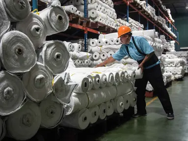 Seorang pekerja menyusun gulungan kain di Trisula Textile Industries, Cimahi, Jawa Barat pada Rabu 22 April 2026, ketika para produsen tekstil menghadapi biaya yang lebih tinggi akibat melonjaknya harga bahan baku petrokimia yang terkait dengan kenaikan harga minyak global. Industri dan produk tekstil (TPT) di Indonesia sedang menghadapi tekanan berat akibat lonjakan harga bahan baku berbasis petrokimia. (Timur MATAHARI/AFP)