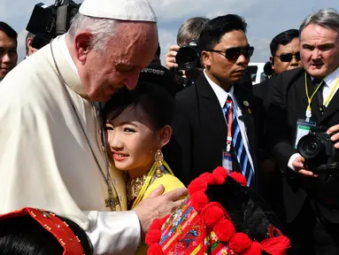 Seorang anak perempuan memeluk Paus Fransiskus saat menyambut kedatangannya di Bandara Internasional Yangon, Myanmar (27/11). Kedatangan Paus Fransiskus disambut oleh ribuan umat Katolik Roma yang memenuhi Yangon. (AFP Photo/Vincenzo Pinto)