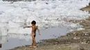 Seorang anak bermain di Sungai Yamuna yang tercemar di New Delhi, Sabtu (8/7). Akibat pertumbuhan populasi dan industrialisasi, Yamuna menjadi salah satu sungai paling tercemar di dunia. (DOMINIQUE FAGET / AFP)