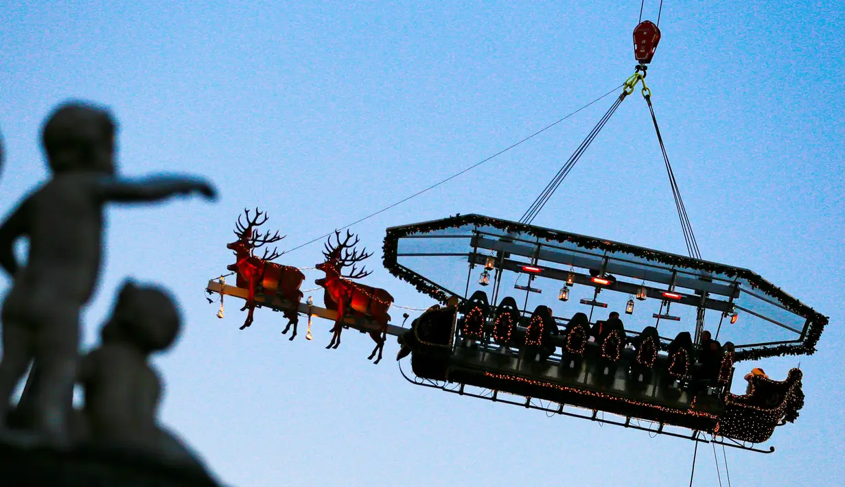 Para tamu menikmati makan malam di "Santa in the sky", yang diangkat dengan crane dan dihias menyerupai "Santa Sleigh" di Brussels, Belgia, 25 November 2016. Tempat ini didekorasi seperti kereta Santa Claus menjelang perayaan Natal. (REUTERS/Yves Herman)