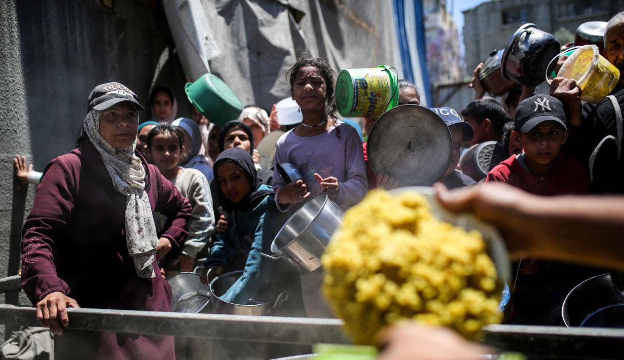 Perserikatan Bangsa Bangsa (PBB), pada Rabu (6/5/2026), memperingatkan bahwa kelaparan masih meluas di seluruh wilayah Gaza. Tampak dalam foto, warga menunggu untuk menerima makanan hangat di kamp pengungsi Palestina, Nuseirat, Jalur Gaza Tengah pada Kamis 7 Mei 2026. (Eyad Baba/AFP)