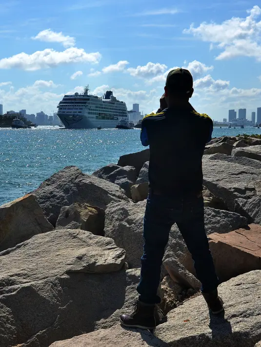 Seorang pria mengambil gambar kapal pesiar milik Carnival, Adonia di Pelabuhan Miami, Florida, Minggu (1/5). Setelah berhenti selama setengah abad, AS dan Kuba lakukan pelayaran bersejarah selama tujuh hari dari Miami ke Havana. (Gaston De CARDENAS/AFP)