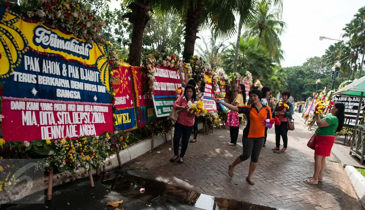 Warga berswafoto di depan karangan bunga untuk Gubernur dan Wakil Gubernur DKI Jakarta Basuki T Purnama (Ahok) dan Djarot Syaiful Hidayat di Balai Kota Jakarta, Rabu (28/4). (Liputan6.com/Gempur M Surya)