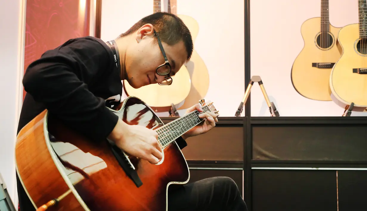 Seorang pria menjajal gitar pada ajang Music China 2020 di Shanghai New International Expo Center, China, 28 Oktober 2020. Music China 2020 diikuti lebih dari 1.000 industri musik dari 11 negara dan kawasan dengan produk-produk baru mereka. (Xinhua/Fang Zhe)