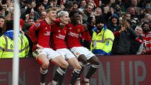 Tiga pemain Manchester United, Rasmus Hojlund, Alejandro Garnacho, dan Kobbie Mainoo duduk di atas papan iklan lapangan Old Trafford sebagai bentuk selebrasi gol yang dicetak ke gawang West Ham United dalam laga pekan ke-23 Premier League 2023/2024, Minggu (4/2/2024) malam WIB. (Paul ELLIS / AFP)