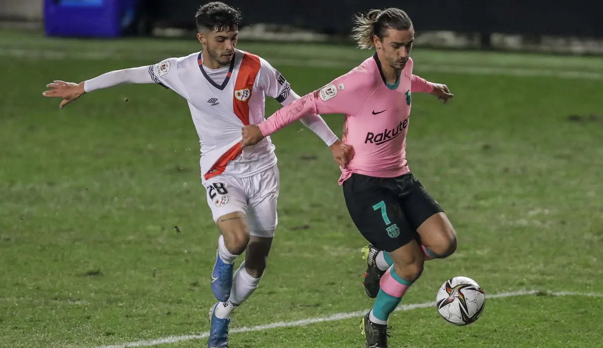 Pemain Rayo Vallecano, Mario Hernandez (kiri) berusaha merebut bola dari pemain Barcelona, Antoine Griezmann pada laga babak 16 Besar Copa del Rey di Vallecas stadium, Madrid, Kamis (28/1/2021). (Foto: AP/Manu Fernandez)