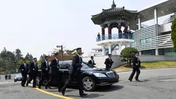 Para pengawal berlari di samping mobil yang membawa Pemimpin Korea Utara Kim Jong-un saat akan makan siang dalam KTT Korea Selatan-Korea Utara di zona demiliterisasi, Panmunjom, Korea Selatan, Jumat (27/4). (Korea Summit Press Pool/AP)