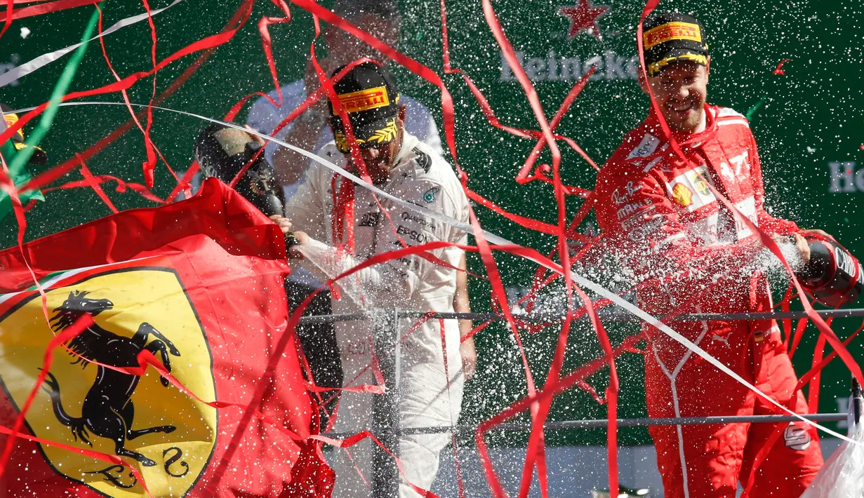 Lewis Hamilton (kiri) dan Sebastian Vettel (kanan) kemenangannya di atas podium usai balapan F1 GP Italia, di arena Monza, Italia (3/9). Dengan kemenangan di Sirkuit Monza, Hamilton kini mengoleksi 238 poin. (AP Photo/Antonio Calanni)