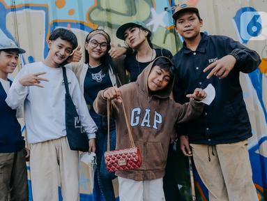 Para remaja dari berbagai daerah di pinggiran Jakarta berpose di Taman Sudirman, Jakarta, Rabu (6/7/2022). Tempat ini viral karena jadi ajang adu fashion anak Citayam, Bekasi hingga Bojong Gede. Mereka mengenakan kemeja flanel oversize, celana model 90-an seperti boot cut atau cutbray, sneakers klasik, dan topi. (Liputan6.com/Faizal Fanani)