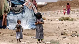Sejumlah anak-anak Yaman berdiri dekat tenda pengungsian di kamp pengungsian di Sanaa, Yaman (15/4). WHO mencatat sebanyak 2,1 juta orang telah terlantar akibat konflik yang terjadi di Yaman. (AFP Photo / Mohammed Huwais)