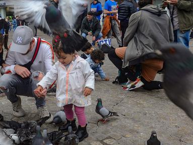 Wisatawan berkumpul sambil memberi makan dan bermain dengan burung merpati di Dam Square, Amsterdam, Belanda, Sabtu (26/5/2024). (merdeka.com/Arie Basuki)