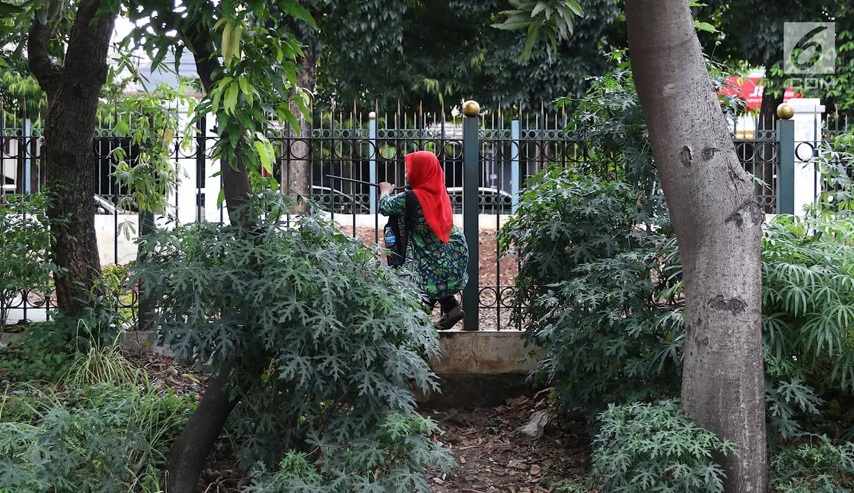 Warga menerobos pagar untuk menyeberangi rel kereta api di kawasan Lenteng Agung, Jakarta, Selasa (19/3). Tidak adanya JPO menyebabkan warga harus menerobos pagar besi, meskipun perilaku tersebut berbahaya bagi keselamatan.(Liputan6.com/Immanuel Antonius)