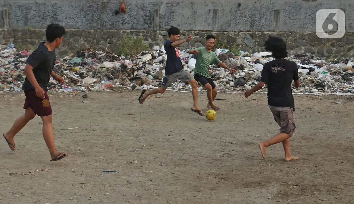 Sejumlah warga bermain sepak bola di antara tumpukan sampah di kawasan Penjaringan, Jakarta, Jumat (1/11/2019). Minimnya lahan bermain di Jakarta membuat warga bermain sepak bola di sekitar tumpukan sampah. (Liputan6.com/Herman Zakharia)