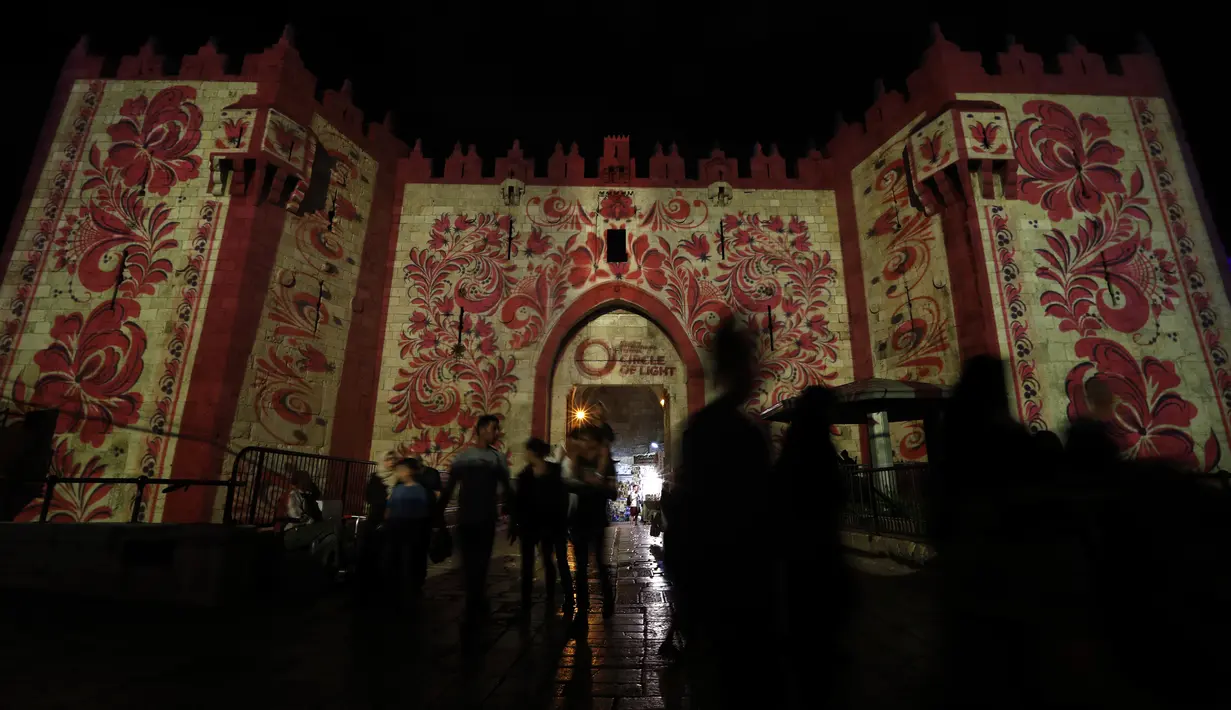 Orang-orang berjalan di dekat gerbang Damaskus selama festival cahaya di kota tua Yerusalem, 28 Juni 2018. Dalam festival yang ke-10 ini, baik anak maupun dewasa bisa datang tanpa dipungut biaya. (AFP / Ahmad GHARABLI)