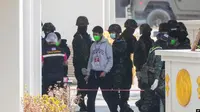 WNI korban kasus 'online scam' di Myanmar timur dikawal tentara Thailand setibanya di Mae Sot, Provinsi Tak Kamis, 27 Februari 2025. Mereka akan dipulangkan ke Indonesia. (Sakchai Lalit/AP)